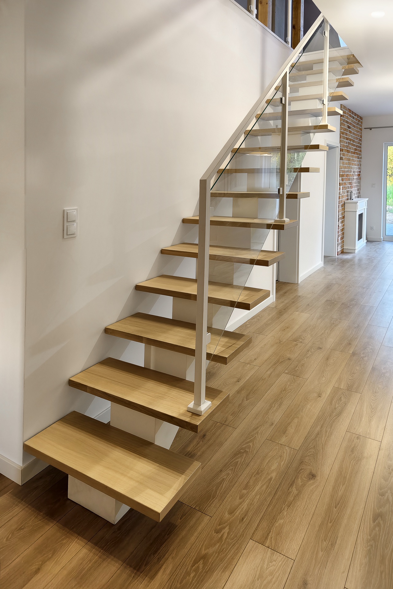 nowoczesne schody na jednej wandze bialej balustrada szklana